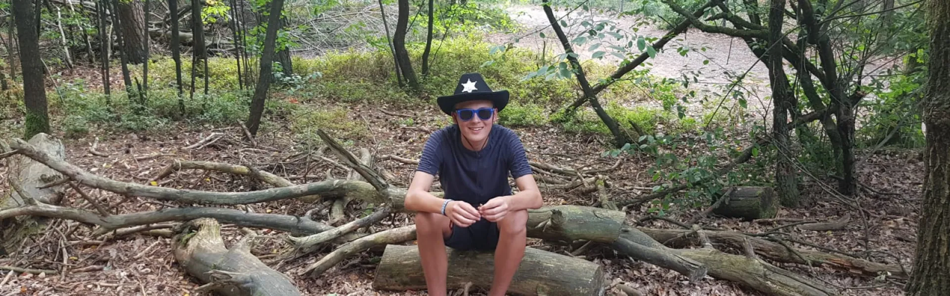 Deelnemer zit op een boomstam in het bos
