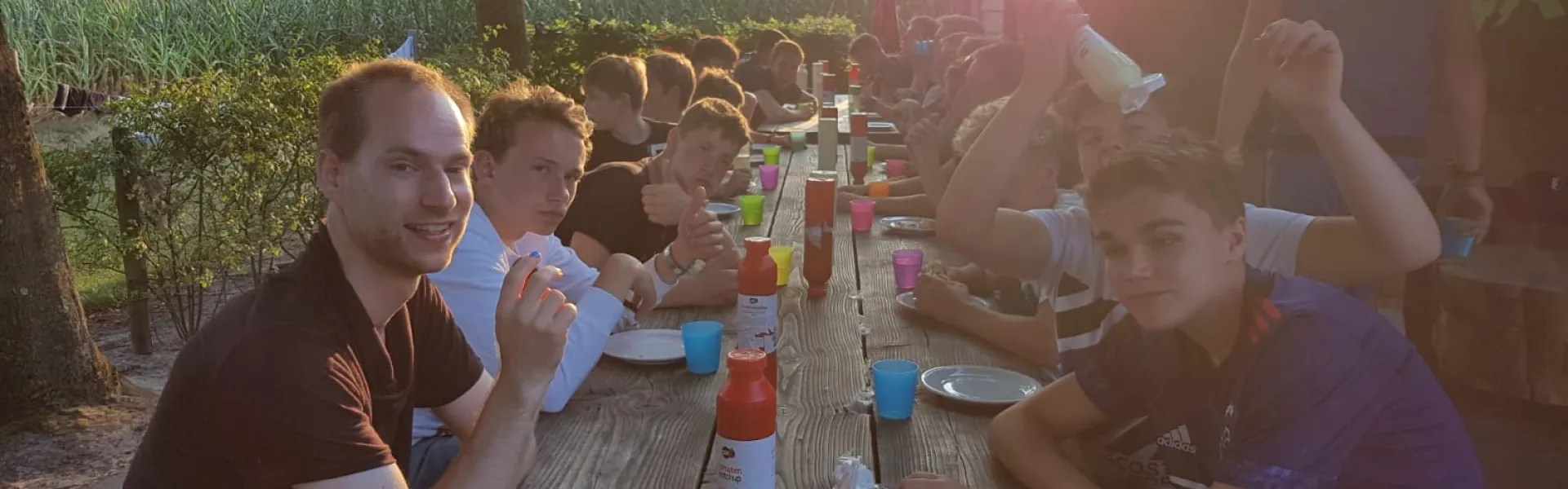 Deelnemers eten aan een tafel in de avondzon