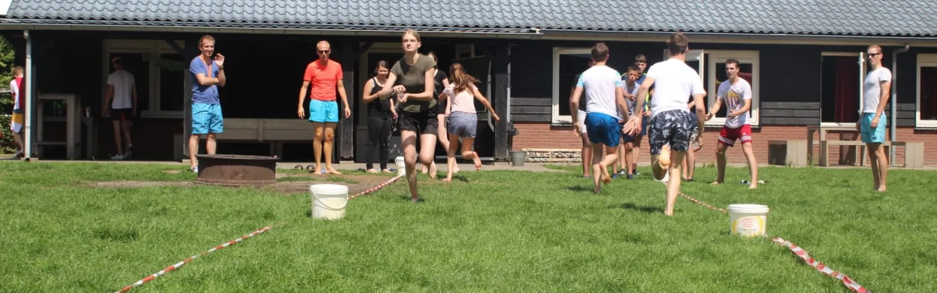 Deelnemers spelen een spel op het grasveld bij het gebouw