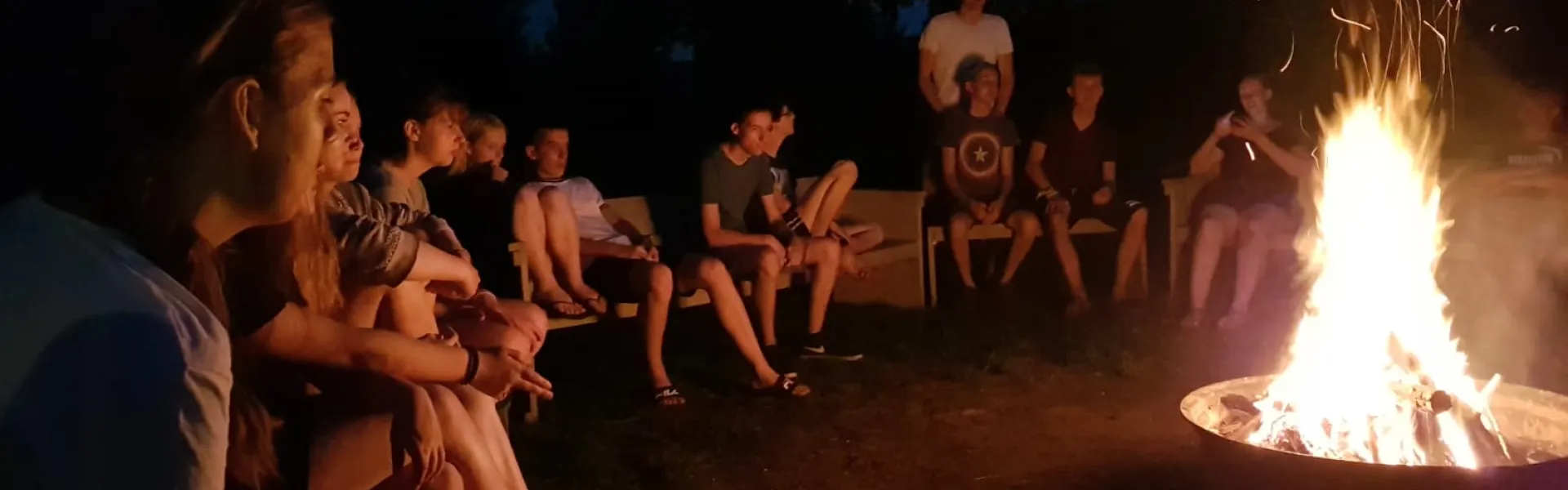 Deelnemers rond een kampvuur in het donker