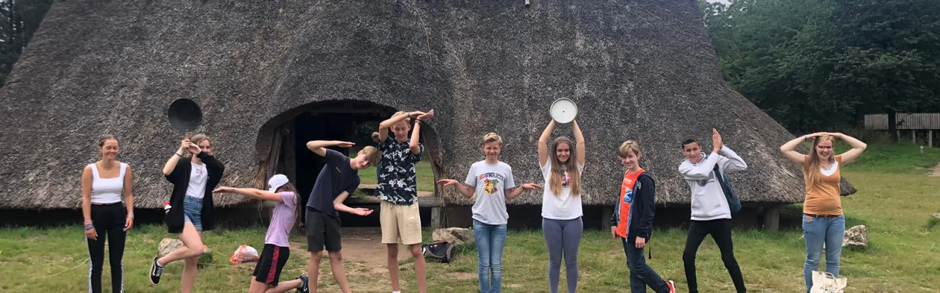 Deelnemers dansen voor een rieten kampgebouw