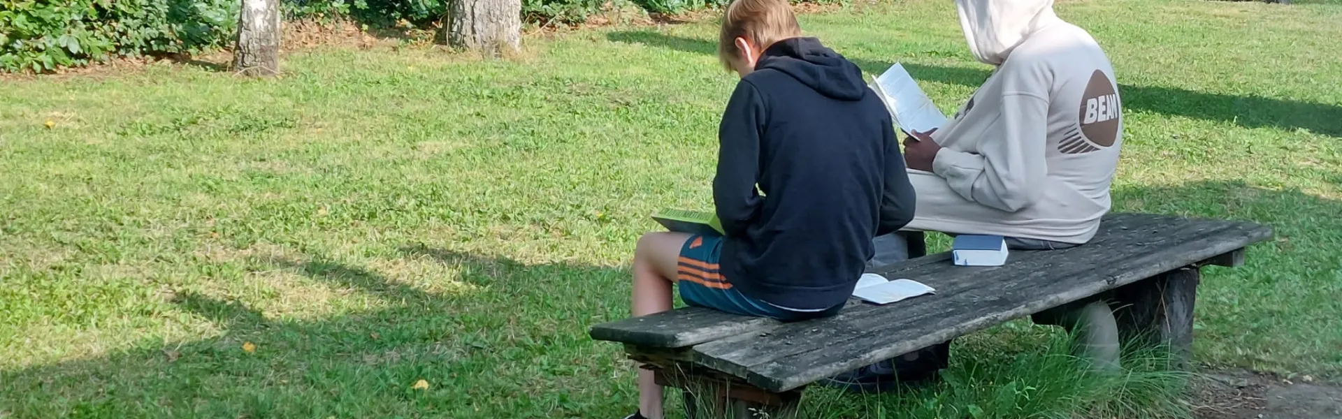Deelnemers zitten op een bank aan de bosrand