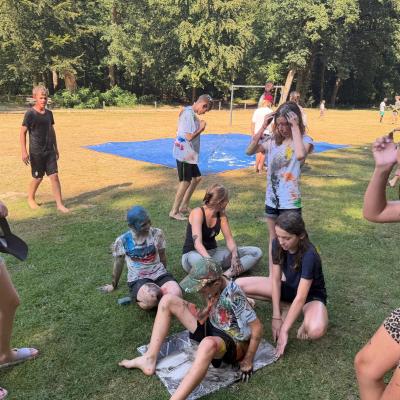 Deelnemers spelen een spel op een blauw zeil