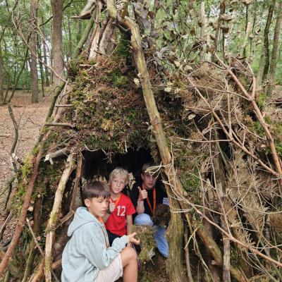 Deelnemer zit in een boomhut van takken